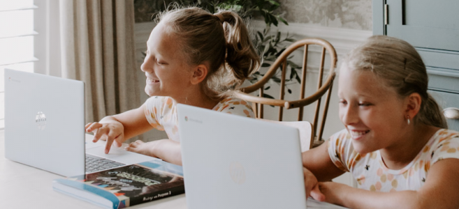 Two girls at home using laptops with Abeka curriculum