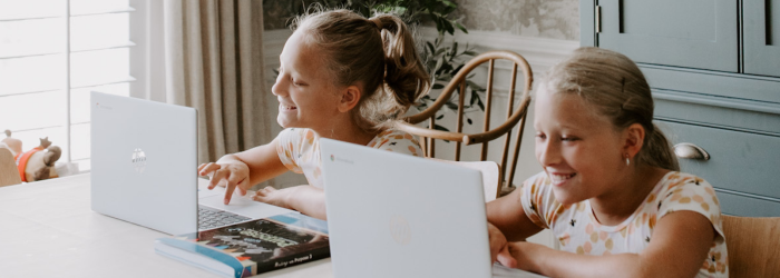 Two girls at home using laptops with Abeka curriculum