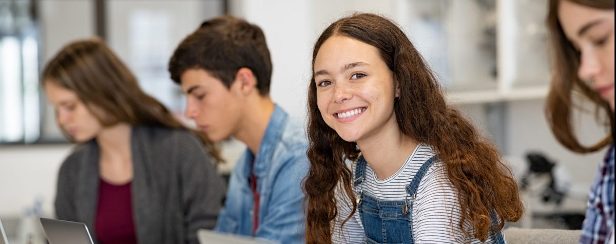 Happy,Young,Woman,Working,On,Laptop,And,Looking,At,Camera