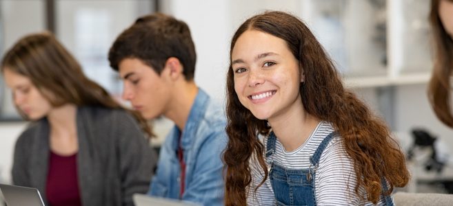 Happy,Young,Woman,Working,On,Laptop,And,Looking,At,Camera